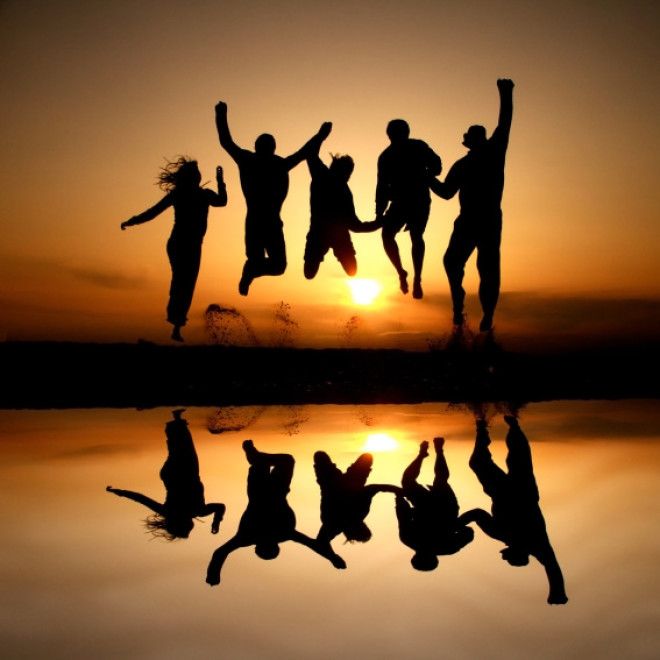 silhouette of friends jumping on beach in sunset