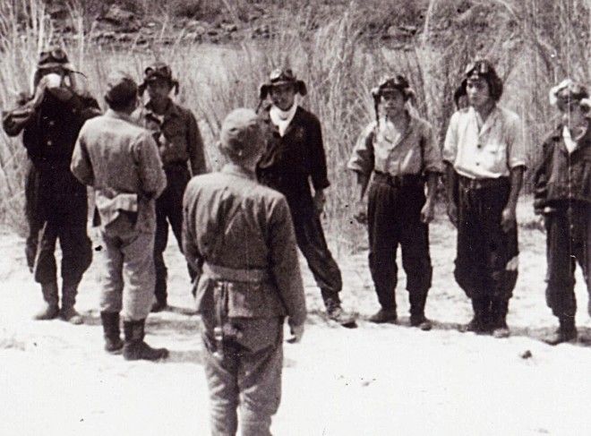 The photograph shows the men of the first actual Kamikaze unit to make an attack on a US ship. The men are being offerred a ceremonial toast of water as a farewell. Yukio Seki, the leader of the first kamikaze unit, is shown with a cup in his hands, and Vice Admiral Takijiro Onishi, who organized the first kamikaze unit, is in the middle of the photo facing the five men of the Shikishima Unit. The man offering the cup is likely Seki's officer, Asaiki Tamai