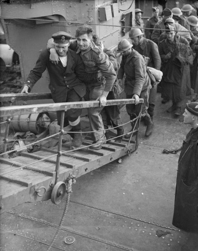 A merchant sailor assists a wounded british soldier up the gangplank from a destroyer Dover 31 May 1940